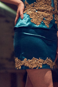 Portion of a teal dress showing fabric and golden embroidery detail
